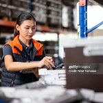 Inventory on Hands in Warehouse and Supply Chain Management System.  Shot of a Female Warehouse Manager is working at a shelf rack to random check inventory on hand balance in a distribution warehouse.