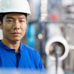 Water Treatment Systems and Management for Bottled Water Manufacturing Industry. Portrait of a Japanese Stationary Engineer working in an ingredient and filtration water storage room to examine quality in the process of water bottling.